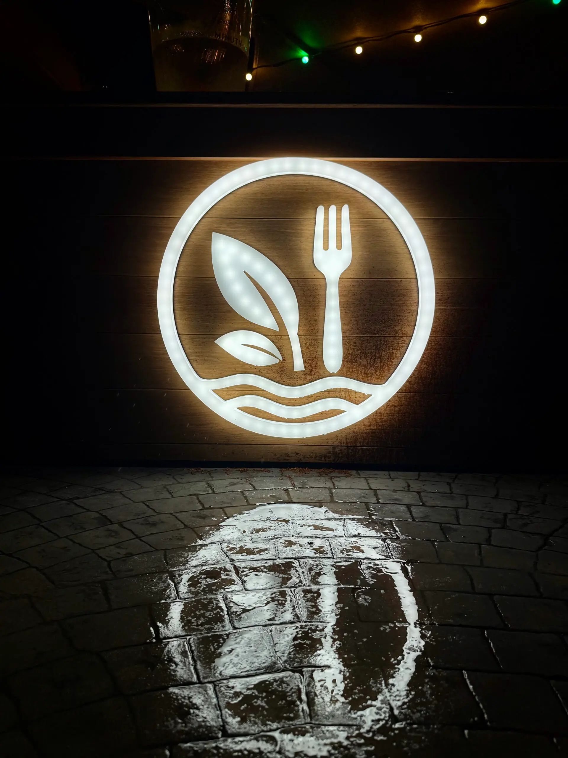 Enseigne lumineuse du restaurant Osmose reflétée sur la terrasse à Saint-Pierre, La Réunion